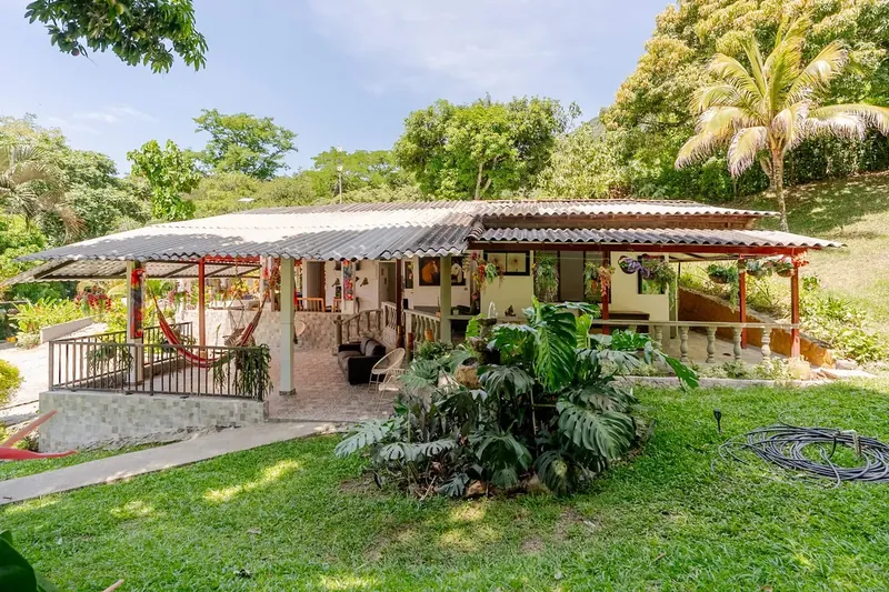 La casa vista desde el jardín, con hamaca en el corredor