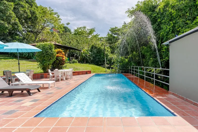 Piscina con fuente, sombrillas y asoleadoras